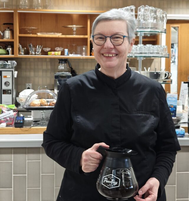 Marja Arola hymyillen Kolmisoinnun edessä